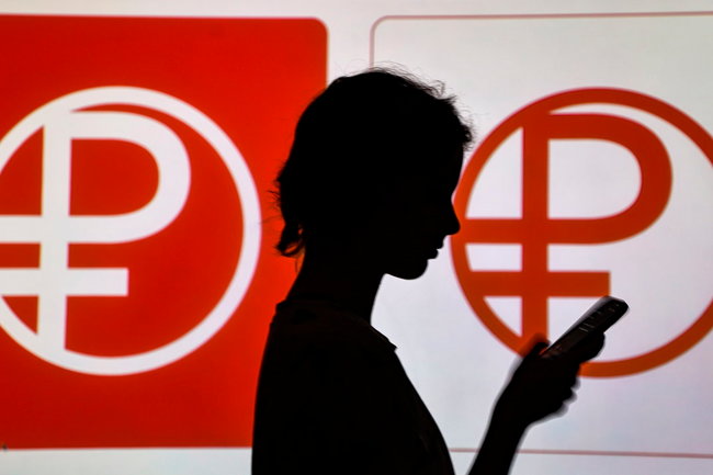Женщина со смартфоном на фоне логотипа цифрового рубля. Первый этап тестирования реальных операций с цифровыми рублями начнется 15 августа. На первом этапе будут тестироваться активные операции - открытие кошельков в цифровых рублях банкам, клиентам (физическим и юридическим лицам), переводы между клиентами и оплата в торгово-сервисных предприятиях. Как сообщали в ЦБ, в тестировании начнут участвовать порядка 600 физлиц и 30 юрлиц в 11 городах России. Согласно списку ЦБ, в пилотную группу вошли Альфа-банк, "ДОМ.РФ", "Ингосстрах банк", ВТБ, ГПБ, "Киви банк", "Ак барс", МТС-банк, Промсвязьбанк, Совкомбанк, "Синара", Росбанк и ТКБ. EPA/ТАСС